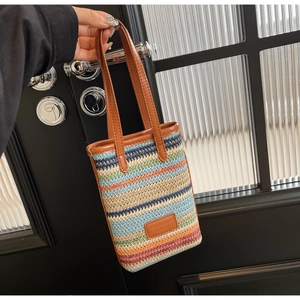 Détail du sac seau tissé à rayures colorées avec poignées en cuir marron et étiquette logo