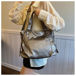Detailed shot of large silver metallic tote bag with rivet studs and adjustable strap