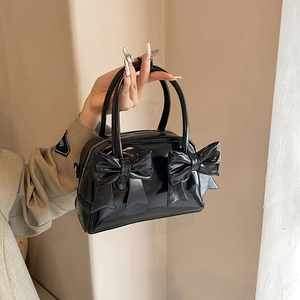 Chic black patent leather bow handbag with vintage pillow shape and top handles