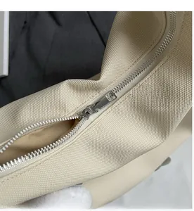 Detail view of smooth silver metal zipper on beige canvas tote bag with textured fabric