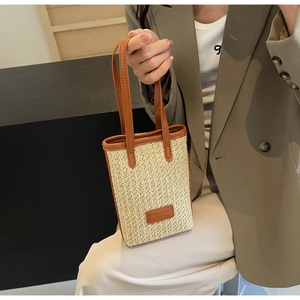 Détail de la texture en paille et de l'écusson en cuir sur le mini sac seau