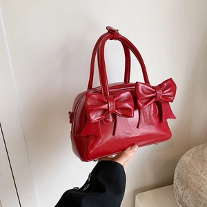 Red patent leather handbag with bow accents and top handles for stylish women