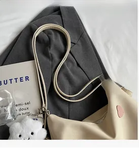 Close-up of cream canvas tote bag featuring heart patch and plush cloud accessory
