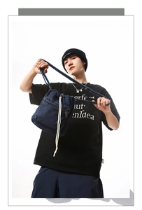 Blue denim drawstring bucket bag on male model with front zipper pocket detail