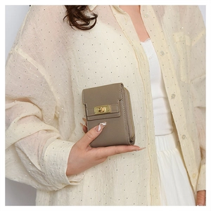 Detail of khaki pebbled leather mini clutch bag featuring a gold twist lock and side zipper