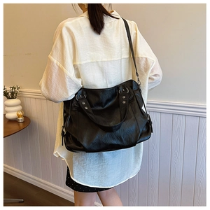 Lifestyle view of large black leather tote bag with silver studs and adjustable strap