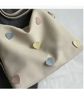 Close-up of cream canvas tote bag featuring colorful stitched heart patches and soft straps