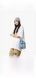 Blue denim drawstring bucket bag with black zipper side pocket and white cord detail