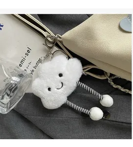 Detail of white plush cloud keychain with embroidery and striped tassels on tote bag