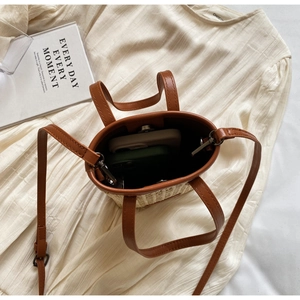 Vue de dessus d'un mini sac seau en paille avec fermeture aimantée et anses en cuir brun