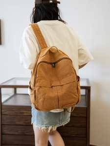 Vue arrière d'un grand sac à dos en toile marron porté par un mannequin en intérieur