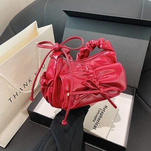 Red glossy pleated crossbody bag with large bow detail in a black gift box