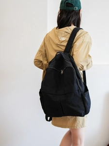 Vue arrière du grand sac à dos en toile noire porté par le mannequin au style minimaliste