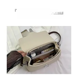 Macro view of beige leather shoulder bag interior showing compartments and storage capacity