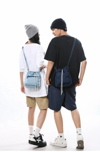 Detail of light and dark blue denim drawstring bucket bags worn by male and female models