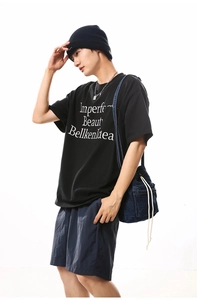 Detail of a black cotton T-shirt with white text print on a street style model