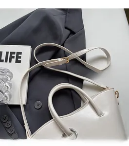 Detail of cream white leather bucket bag with silver ring and adjustable strap