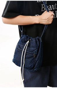 Detail view of deep blue denim bucket bag featuring drawstring closure and zipper pocket