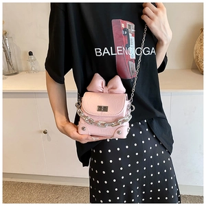Detail van roze crossbodytas met grote strikdecoratie en zilveren metalen kettingriem