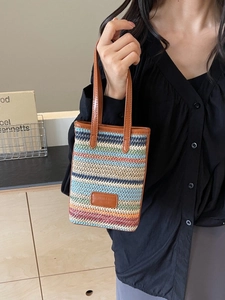 Mini sac seau tissé à rayures avec bordure en cuir marron présenté dans une vue latérale