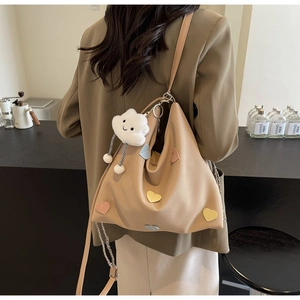 Detail of soft earth-tone tote bag with colorful heart patches and cloud charm on a model