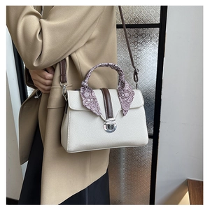 Detail of off-white lychee texture leather bag with paisley scarf handle and silver lock
