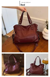 Detailed view of large red faux leather tote bag with rivet accents and shoulder strap