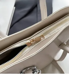 Detail of smooth pale gold metal zipper on cream white leather bucket handbag