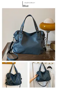 Detail of blue tote bag with litchi texture, golden rivets and adjustable strap