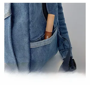 Close-up of blue denim backpack showing the practical side pocket with smooth texture