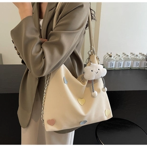 Detail view of cream canvas tote bag featuring colorful heart patches and cloud charm