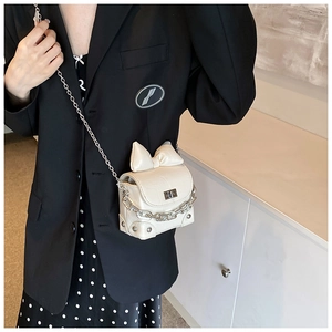 Detail of a creamy white mini crossbody bag with crocodile pattern and bow decoration