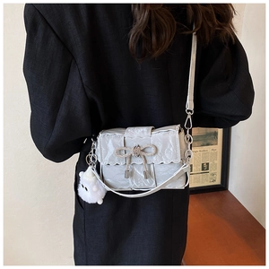 Détail du nœud tissé sur un sac à bandoulière plissé gris avec charme en peluche