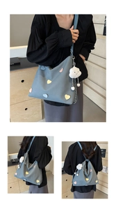 Detail view of gray canvas tote bag featuring colorful heart patches and cloud charm