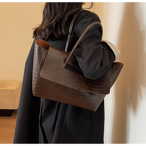 Close-up of deep brown crocodile embossed leather tote bag worn on shoulder