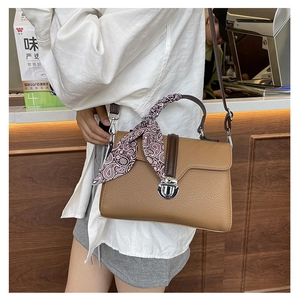Detail of brown litchi pattern handbag with silver metal buckle and silk scarf on handle