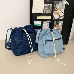 Fashionable denim drawstring bucket bags in dark and light blue with front zipper pocket