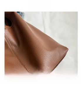 Close-up of premium brown lychee grain leather texture and durable stitching on tote bag