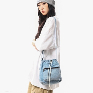 Light blue denim drawstring bucket bag shown on a model with street fashion style