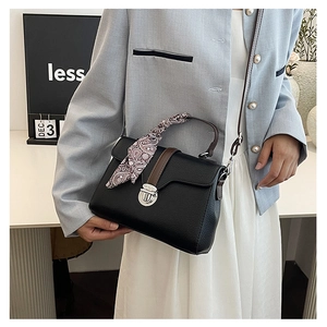 Close-up of black lychee texture handbag with silk scarf handle and silver metal lock