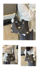 Detail view of brown canvas tote bag with colorful heart patches and cloud charm pendant