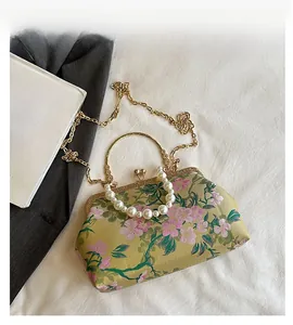 Detail view of floral embroidery handbag with pearl handle and golden heart clasp