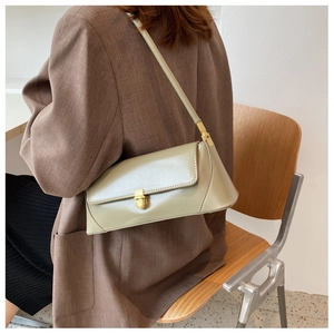 Close-up of light olive leather underarm bag with gold clasp shown on shoulder