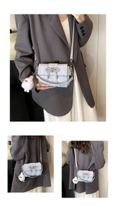 Détail du sac en cuir plissé bleu clair avec nœud en strass et pompon en peluche