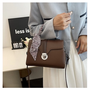 Brown litchi grain leather handbag detail with silver twist lock and paisley silk scarf