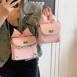 Pink mini crossbody bag with a large bow, quilted texture and silver chain strap