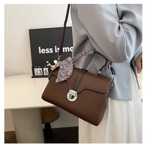 Detail of dark brown pebble leather crossbody bag with decorative scarf and silver metal lock