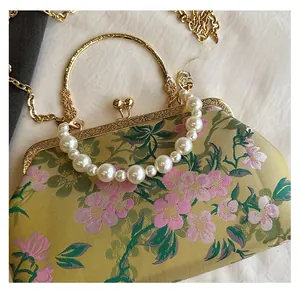 Close-up of retro floral jacquard evening bag with pearl chain and gold metal handle
