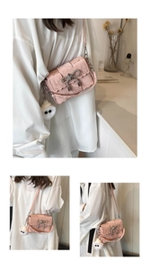 Gros plan du sac bandoulière rose avec nœud en strass et pendentif peluche blanc