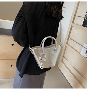 Silver metallic bucket bag with bow charm, crossbody style shown on model in urban outfit
